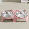 A pink stainless steel double pet bowl with an anti-tip design sitting on a light surface.