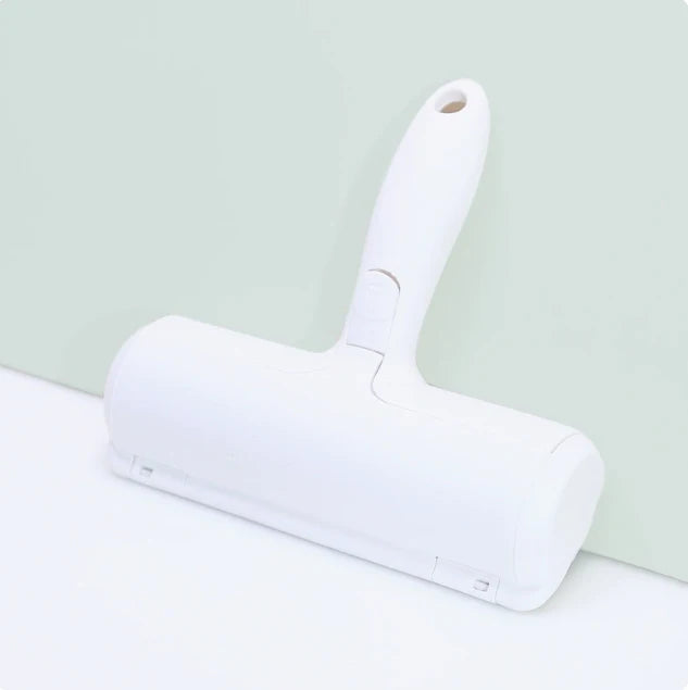 A white reusable pet hair remover brush with a handle is shown against a light green background.