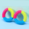 A set of colorful rubber chew toys for dogs, featuring pink, yellow, and blue textured rings.