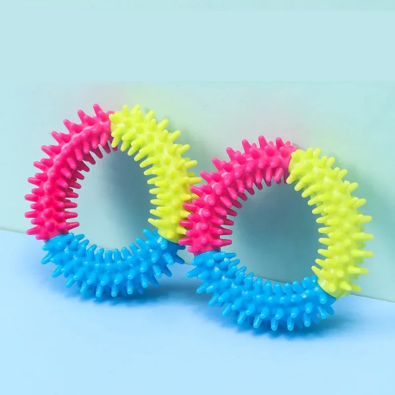 A set of colorful rubber chew toys for dogs, featuring pink, yellow, and blue textured rings.