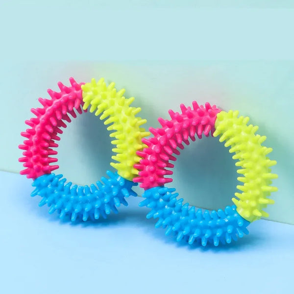 A set of colorful rubber chew toys for dogs, featuring pink, yellow, and blue textured rings.
