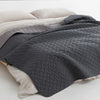 A dark gray reversible waterproof pet mat with a quilted texture is shown folded on a light beige surface.