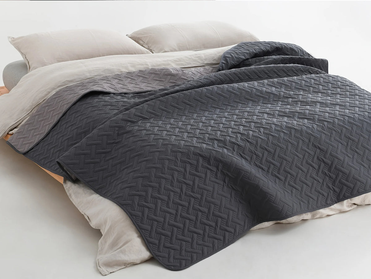 A dark gray reversible waterproof pet mat with a quilted texture is shown folded on a light beige surface.
