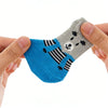 A hand is holding a blue knitted anti-scratch pet sock with a gray animal face design.