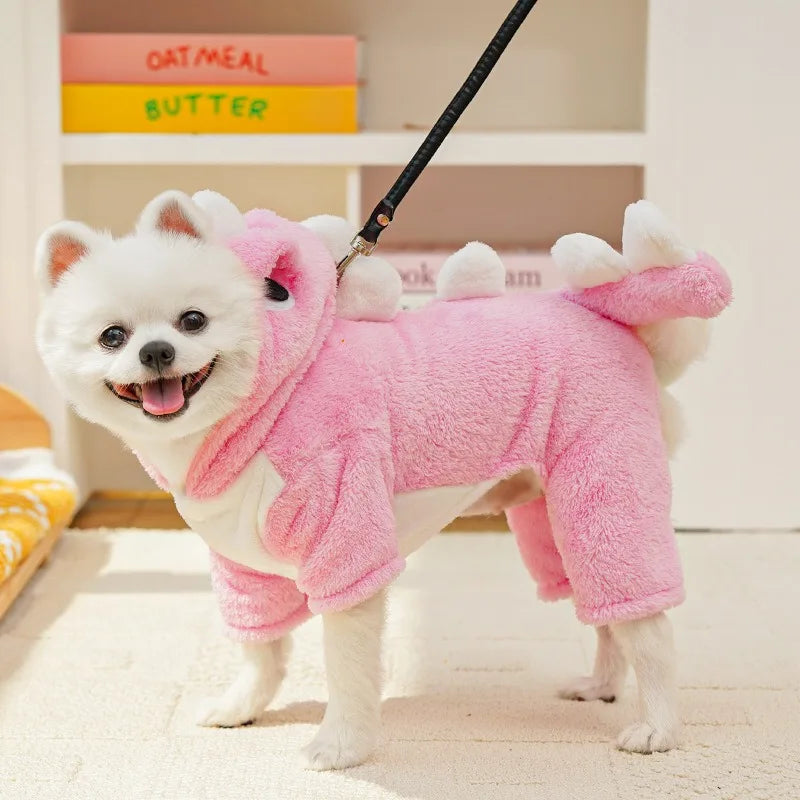 A white dog plush toy wearing a pink fleece hoodie with animal ears, standing on a light rug.