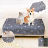 A fluffy dog and a cat sitting on a dark gray pet urine pad with paw print designs.