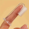 A hand holds a clear silicone pet toothbrush with white bristles, demonstrating the product for dogs and cats.