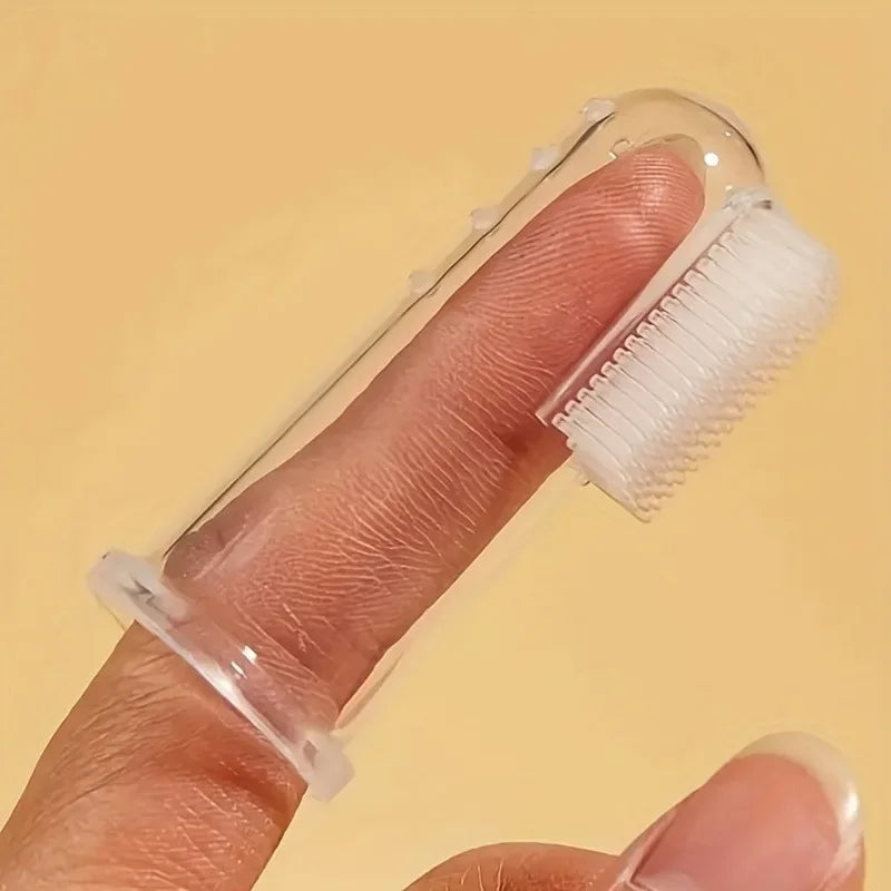 A hand holds a clear silicone pet toothbrush with white bristles, demonstrating the product for dogs and cats.