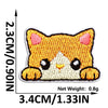 An embroidered patch of a cute orange cat face with white accents on a beige background.