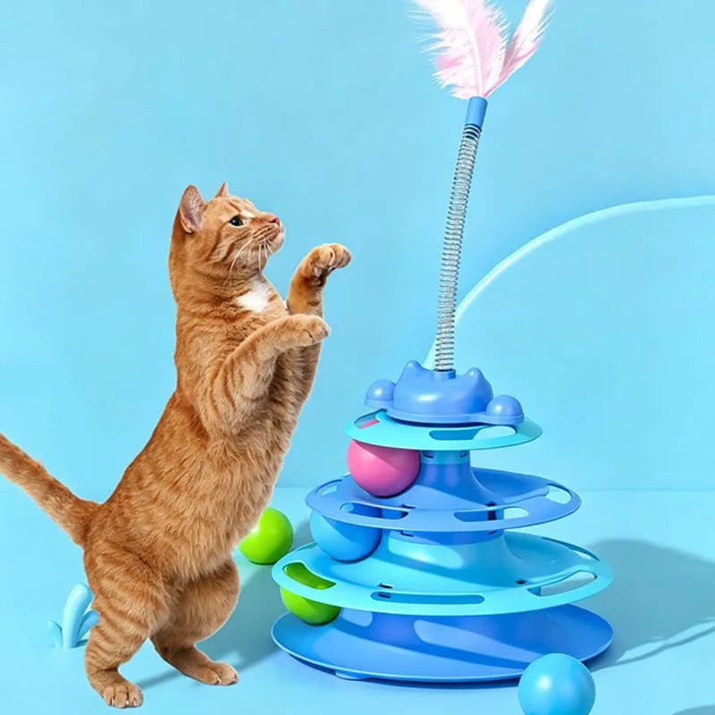 An orange tabby cat interacts with a blue interactive toy featuring a feather wand and rolling balls.