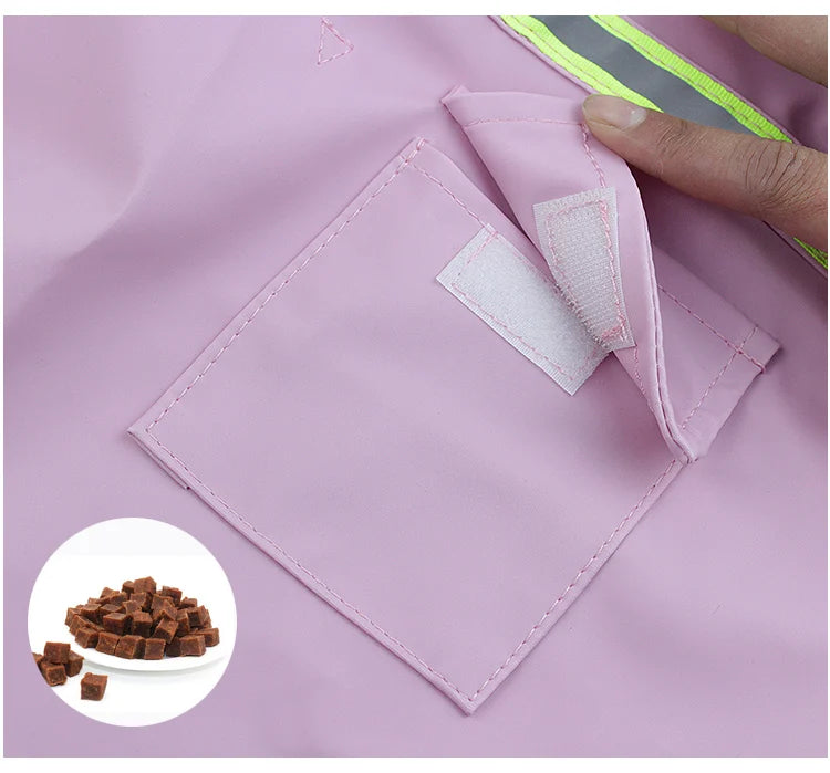 A pink waterproof reflective dog raincoat with a patch detail is shown on fabric.