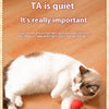 A white cat is playing with a red ball toy on the floor.