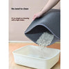 A hand is shaking a gray double layer cat litter mat into a white plastic container.