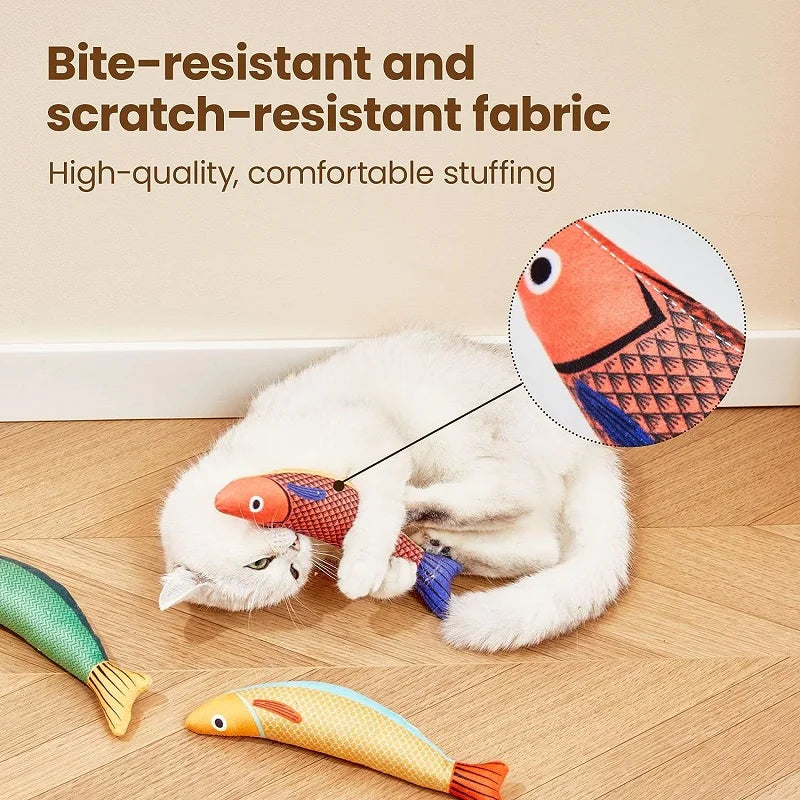 A white cat is playing with a textured, bite-resistant fabric fish plush toy.