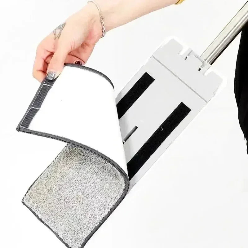 A hand holds a white reusable microfiber mop pad attached to a mop handle.