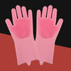A pair of pink silicone pet grooming gloves for dogs and cats displayed on a reddish-brown surface.