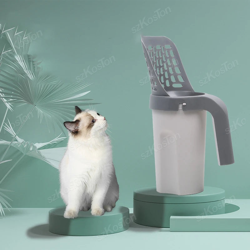 A gray cat litter shovel with a refill bag is shown next to a white cat on a green surface.
