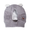 A gray knit beanie with ear muffs and a brown accent patch for dog owners