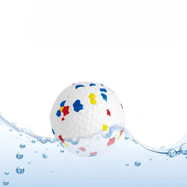 A white chew ball with colorful plastic inserts is submerged in clear water.