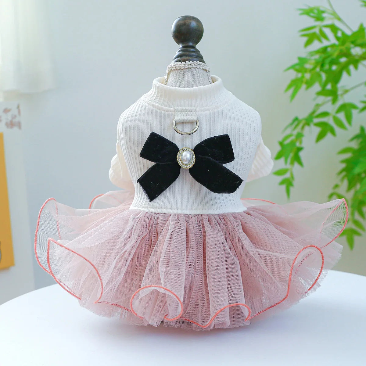 A light pink lace pet dress for dogs and cats with a black bow and sheer tulle skirt.