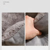 Close-up of a hand resting on the fluffy, soft gray fabric of a plush cat bed cushion.