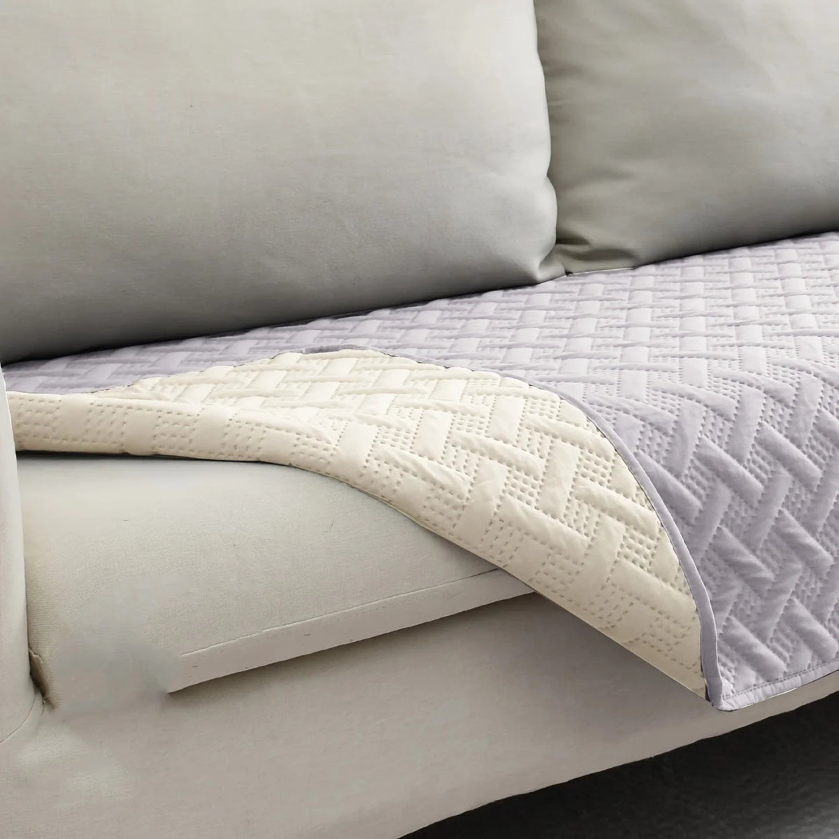A light gray reversible waterproof pet mat with a quilted texture and non-slip base is shown on a sofa.