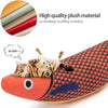A tabby cat is resting on a orange fish-shaped plush toy with a textured pattern.