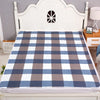 A plaid bed protector pad featuring blue, gray, and white checks displayed on a white wooden headboard.