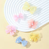 A collection of pink, yellow, and blue pet hair bow clips displayed on a white ribbed plate.