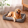 A golden retriever lies comfortably on a gray orthopedic dog bed indoors.