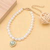 Un délicat collier de perles avec un pendentif de pierre verte et une chaîne en or.