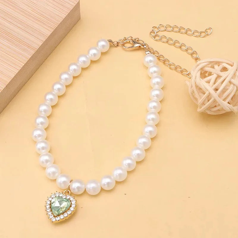 Un délicat collier de perles avec un pendentif de pierre verte et une chaîne en or.