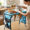 A woman is using a foldable pet grooming hammock to bathe and trim a cat.