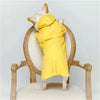 A dog wearing a yellow waterproof raincoat is standing on a wooden coat rack.