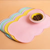 A stack of colorful silicone pet feeding mats, including a pink mat with a yellow mat underneath, holding a small bowl of pet