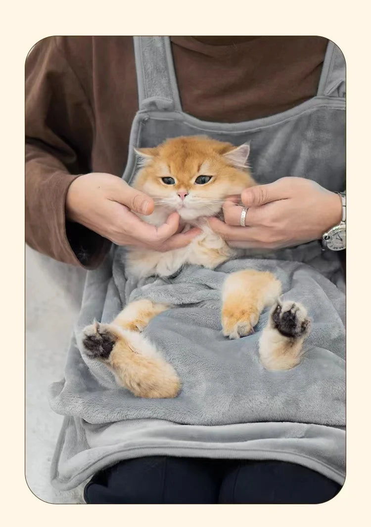 Una persona sostiene un gatito naranja peludo en un pet carrier al aire libre mientras lleva un delantal gris.
