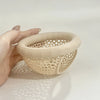 A hand holds a beige aquarium decor hammock made of woven plastic for betta and shrimp tanks.
