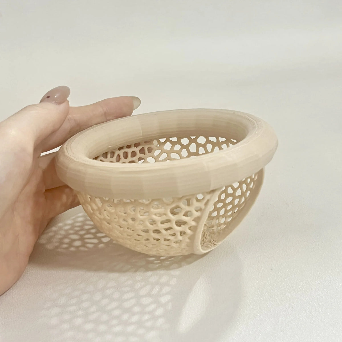 A hand holds a beige aquarium decor hammock made of woven plastic for betta and shrimp tanks.