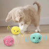 A fluffy cat is interacting with three colorful, sound-making toys on a wooden floor.