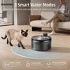 A black pet water fountain sits on a light wooden floor with a cat nearby, demonstrating its three smart water modes.