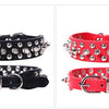 Two adjustable leather spiked dog collars, one black and one red, featuring silver buckles.