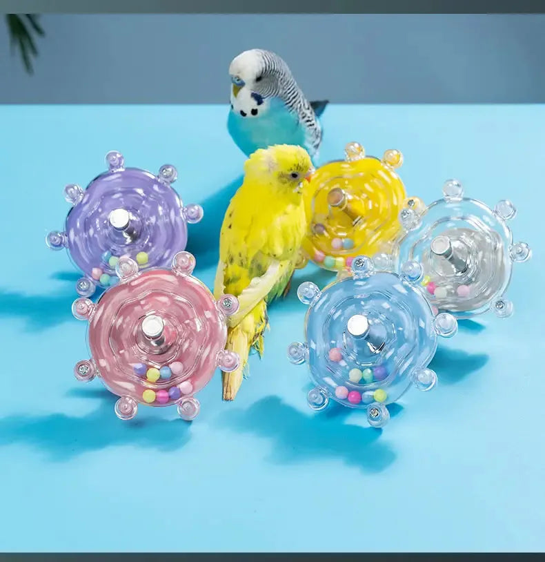 Eine Sammlung bunter, rotierender Papageit-Spielzeuge und Futterdispenser mit einem kleinen Vogel und einem Pinguin.