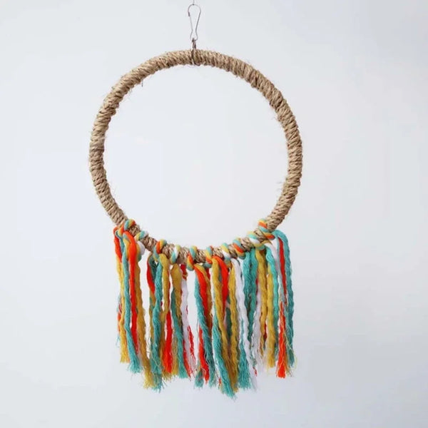 A hand-carried wooden parrot perch toy with a round woven rope and colorful tassels hanging from it.