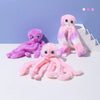 Three fluffy octopus plush toys in shades of purple and pink sitting on a white surface.