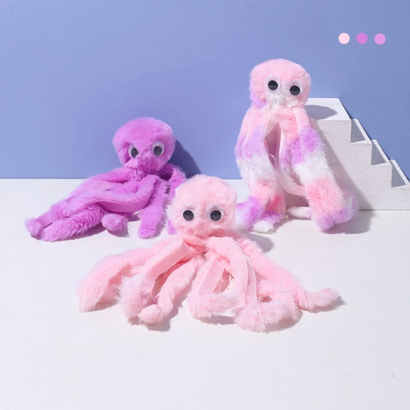 Three fluffy octopus plush toys in shades of purple and pink sitting on a white surface.