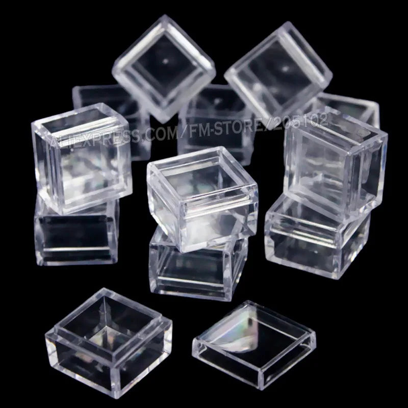 A collection of clear square storage boxes or containers for craft supplies arranged on a dark background.