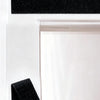 Black adhesive hook and loop fibers used for no-drill installation on a white door frame.