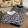A black and white patterned knit sweater for dogs is displayed next to a box.