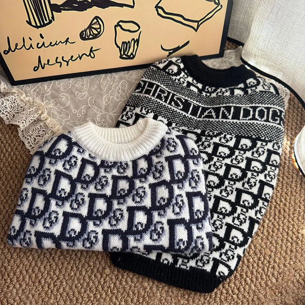 A black and white patterned knit sweater for dogs is displayed next to a box.