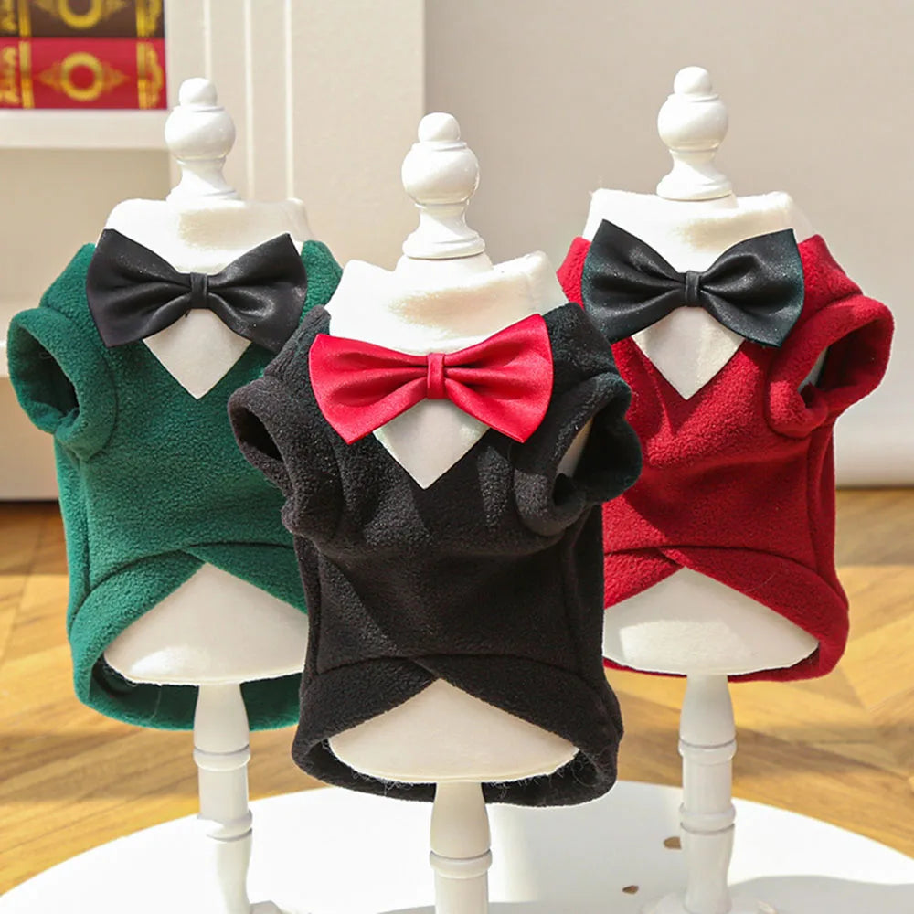 Three display mannequins show warm fleece dog tuxedo costumes with bow ties in green, black, and red.